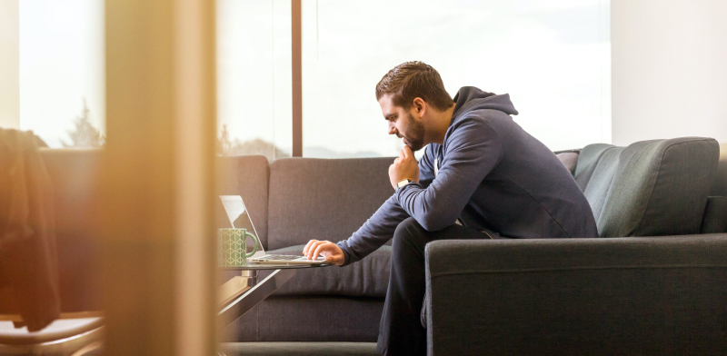 Man sitting on couch working on laptop from home