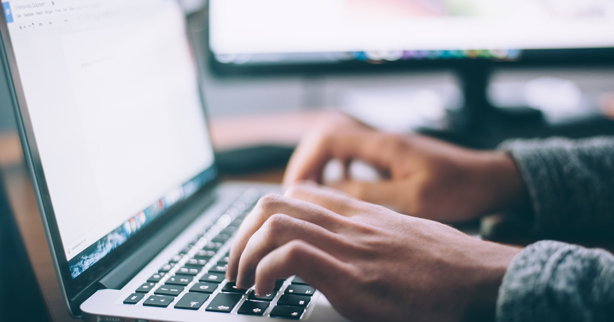 person using a laptop to compose a document