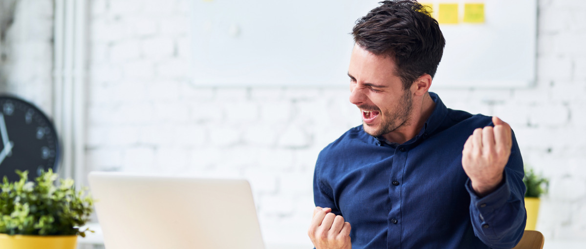 man fist pumping at desk