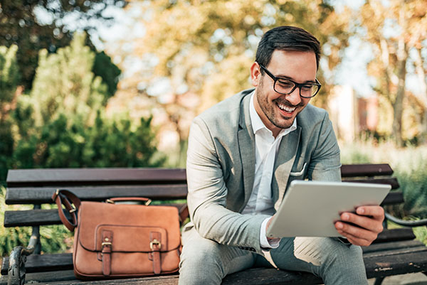 Man using tablet on park bench