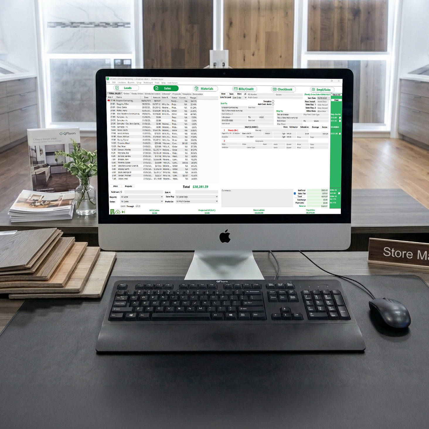 QFloors desktop on store manager's desk in a flooring showroom